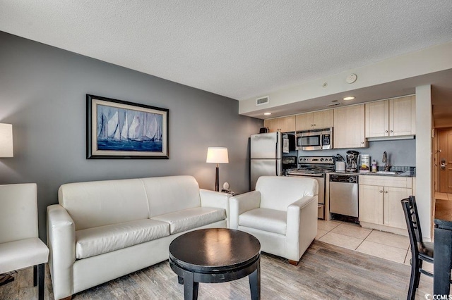 living area featuring light wood-style flooring and a textured ceiling