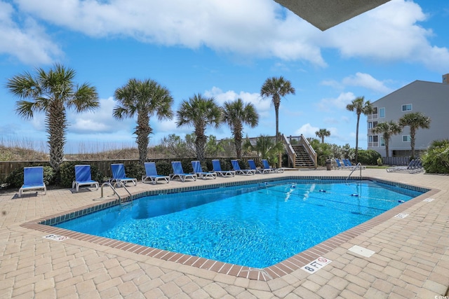 community pool featuring a patio, fence, and stairs