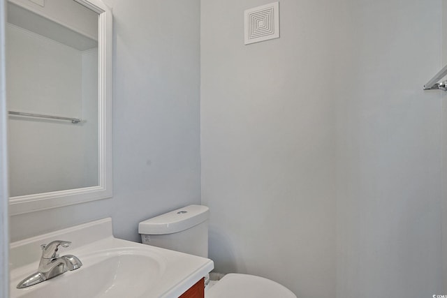 half bathroom with toilet, visible vents, and vanity