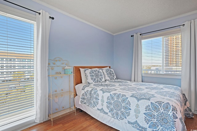 bedroom with crown molding, a textured ceiling, and wood finished floors