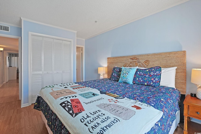 bedroom featuring crown molding, visible vents, wood finished floors, and a closet