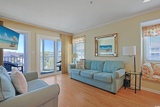 living room with crown molding, baseboards, and light wood-style flooring