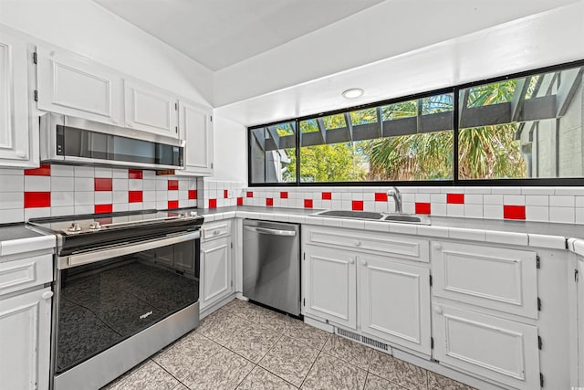 7300 Porcher Dr Unit 11, Myrtle Beach, SC 29572 - kitchen featuring appliances with stainless steel finishes, white cabinetry, backsplash, and tile countertops