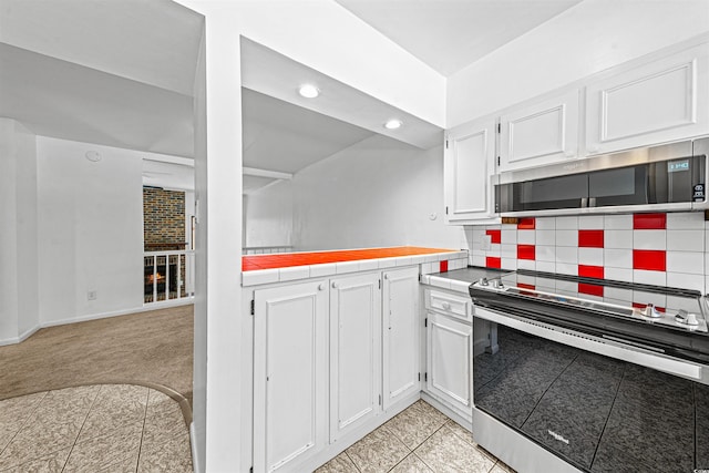 7300 Porcher Dr Unit 11, Myrtle Beach, SC 29572 - kitchen with appliances with stainless steel finishes, white cabinetry, decorative backsplash, tile counters, and recessed lighting