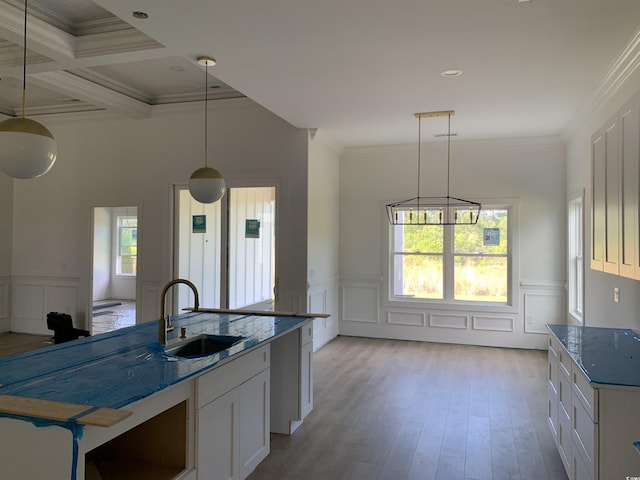 kitchen featuring a decorative wall, wainscoting, ornamental molding, and a sink