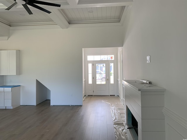 foyer entrance with beam ceiling, ornamental molding, light wood finished floors, a ceiling fan, and coffered ceiling