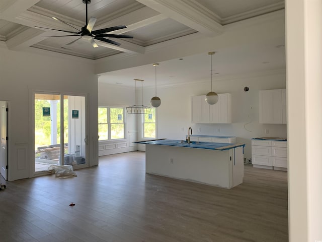 kitchen featuring white cabinetry, beamed ceiling, light wood-type flooring, and a sink