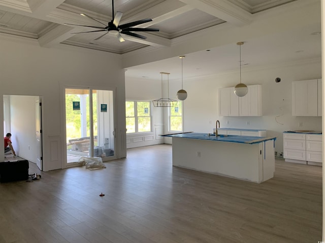 kitchen featuring crown molding, open floor plan, wood finished floors, and beamed ceiling