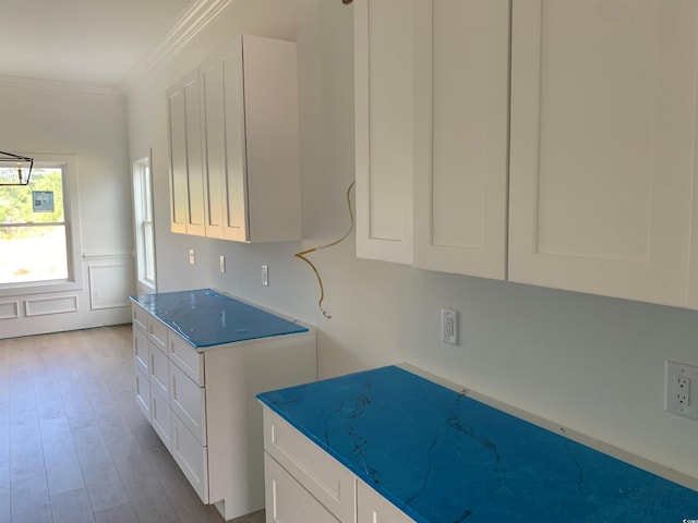 kitchen with ornamental molding, white cabinetry, and wood finished floors
