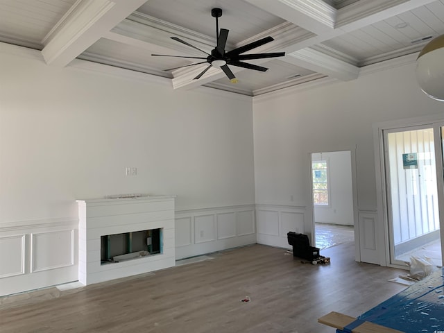 unfurnished living room featuring wood finished floors, beam ceiling, crown molding, a ceiling fan, and coffered ceiling