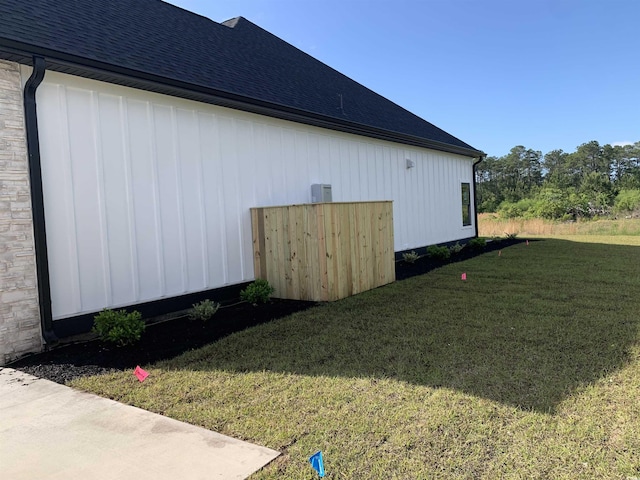 view of property exterior featuring roof with shingles and a lawn