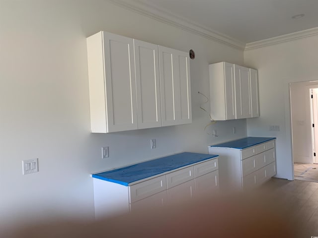 kitchen with light wood-type flooring, ornamental molding, and white cabinetry