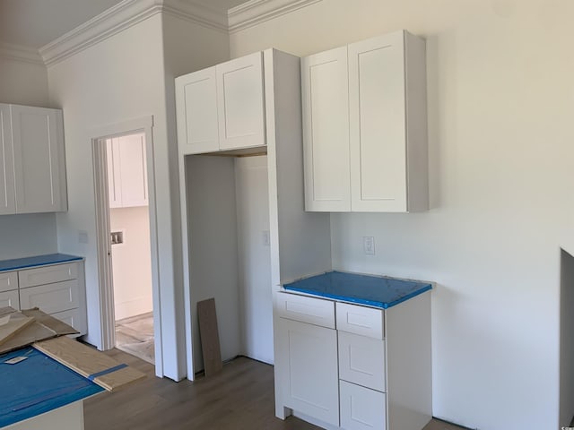 kitchen featuring white cabinets, crown molding, and wood finished floors