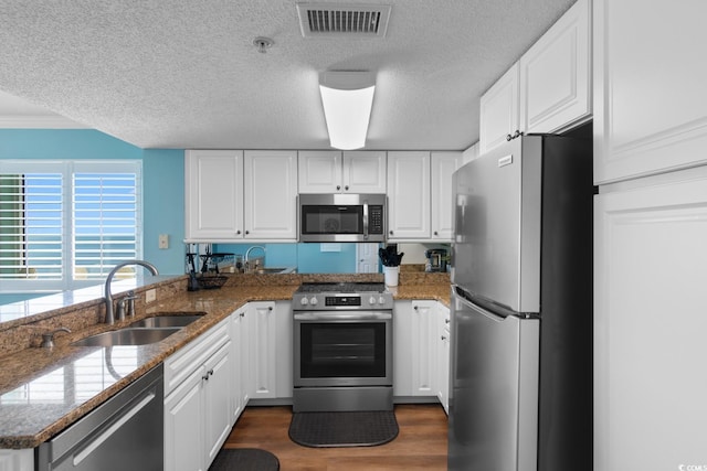 501 S Ocean Blvd Unit 1006, North Myrtle Beach, SC 29582 - kitchen with appliances with stainless steel finishes, a sink, a textured ceiling, a peninsula, and white cabinets