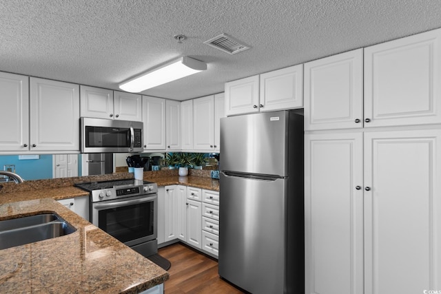 501 S Ocean Blvd Unit 1006, North Myrtle Beach, SC 29582 - kitchen with stainless steel appliances, a sink, white cabinets, dark wood-style floors, and a textured ceiling
