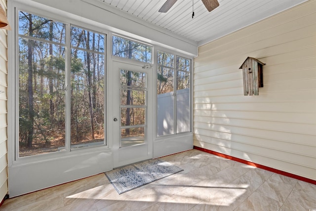 unfurnished sunroom featuring a ceiling fan and plenty of natural light