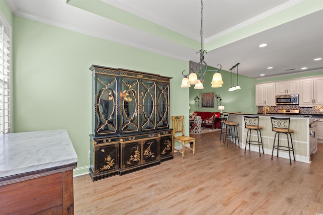 dining area featuring crown molding, light wood finished floors, a chandelier, and recessed lighting