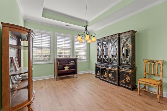 sitting room with a chandelier, wood finished floors, healthy amount of natural light, crown molding, and baseboards