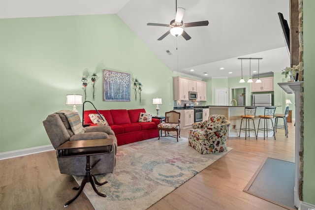 living room featuring ceiling fan, high vaulted ceiling, light wood-type flooring, baseboards, and recessed lighting