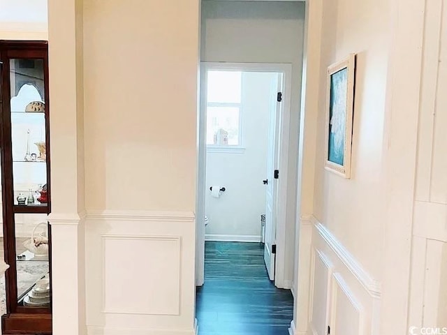 corridor featuring baseboards and dark wood-type flooring