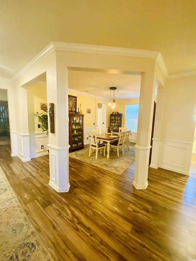living area featuring a decorative wall, ornamental molding, and dark wood-style flooring