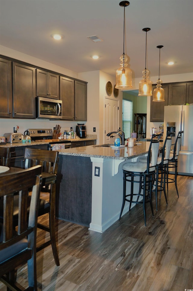 kitchen featuring dark brown cabinets, stainless steel appliances, and dark wood-type flooring
