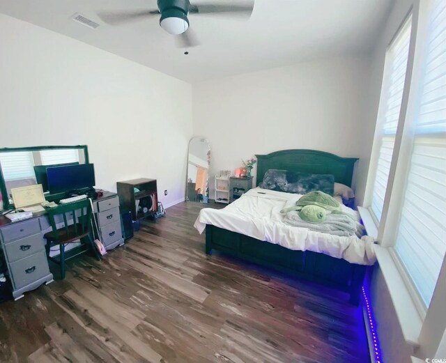 bedroom with ceiling fan, wood finished floors, multiple windows, and visible vents