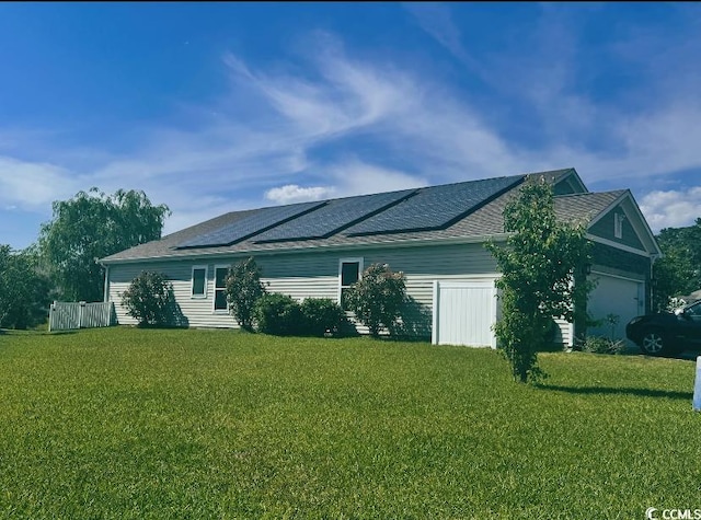 view of side of property featuring a garage, a yard, and solar panels