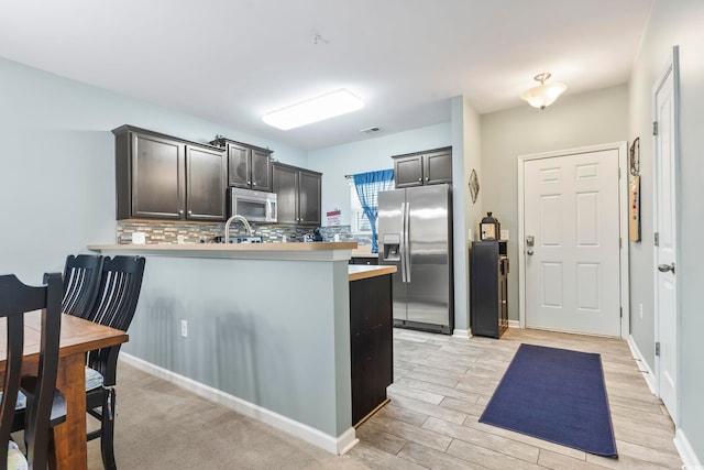6253 Catalina Dr Unit 713, North Myrtle Beach, SC 29582 - kitchen featuring stainless steel appliances, decorative backsplash, a peninsula, light countertops, and light wood-type flooring