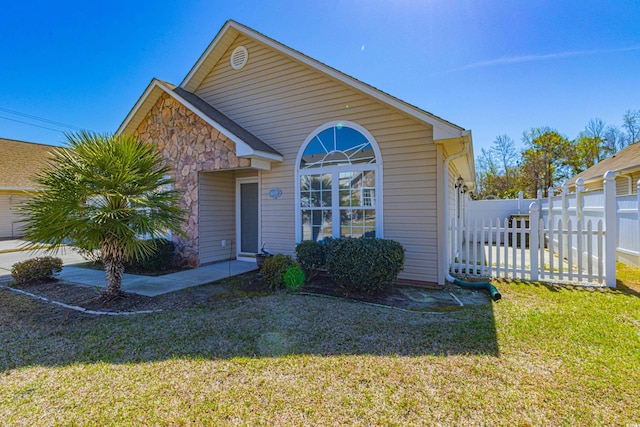 view of front of home featuring fence, stone siding, and a front yard