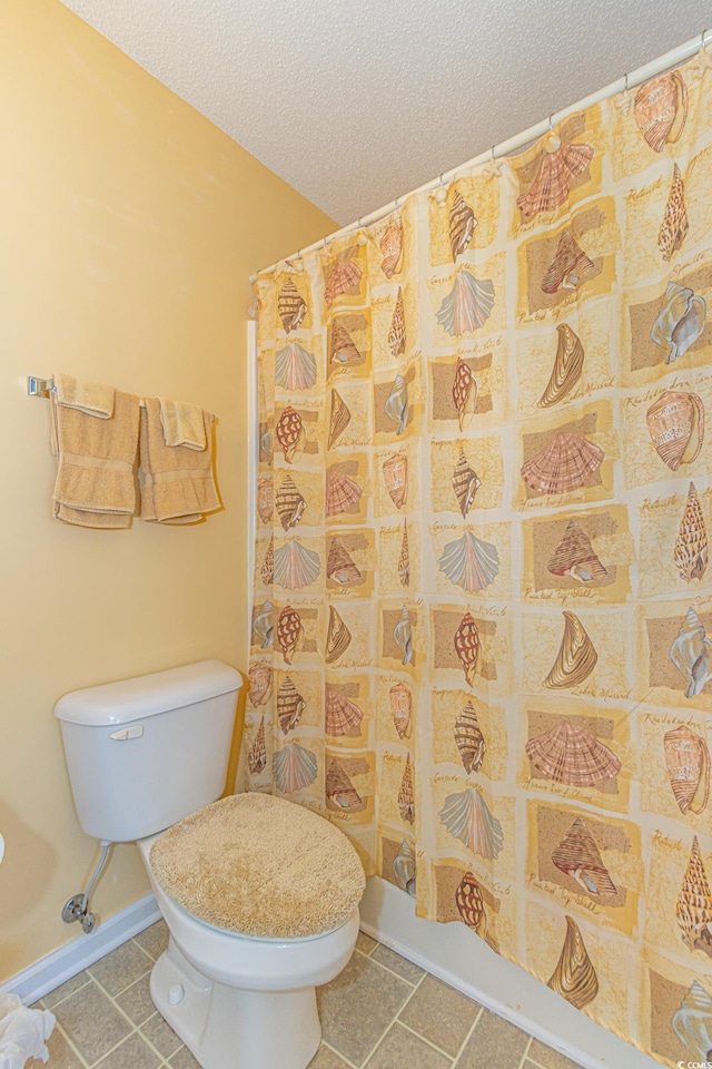 full bathroom with tile patterned flooring, curtained shower, toilet, baseboards, and a textured ceiling