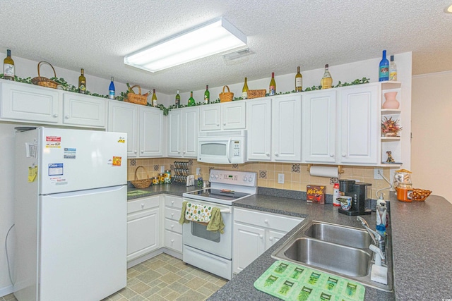 kitchen featuring a sink, dark countertops, decorative backsplash, and white appliances