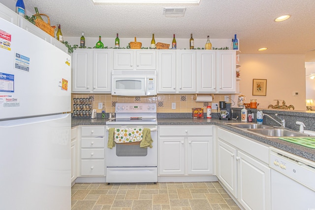 kitchen featuring white cabinets, dark countertops, a sink, white appliances, and a textured ceiling