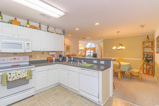 kitchen featuring white appliances, a peninsula, a textured ceiling, and an inviting chandelier