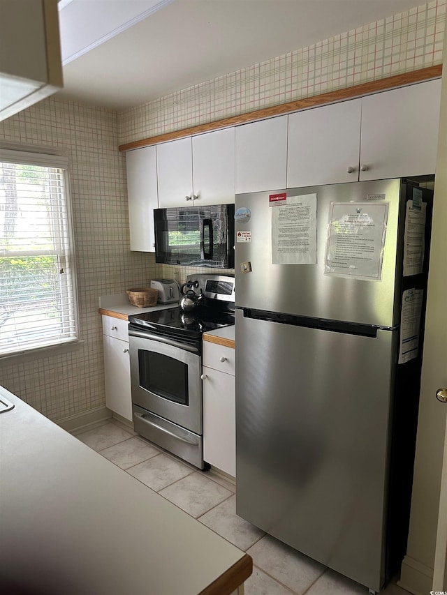 kitchen with appliances with stainless steel finishes, white cabinetry, light countertops, and light tile patterned flooring