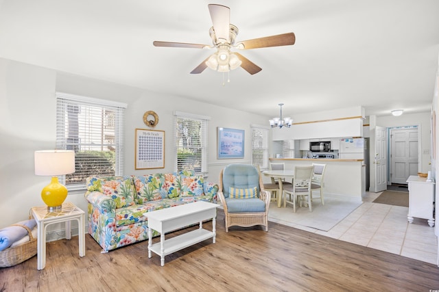 living room featuring a chandelier, a ceiling fan, and light wood-style flooring