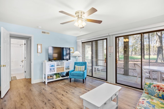 living area with plenty of natural light, ceiling fan, and light wood-style flooring