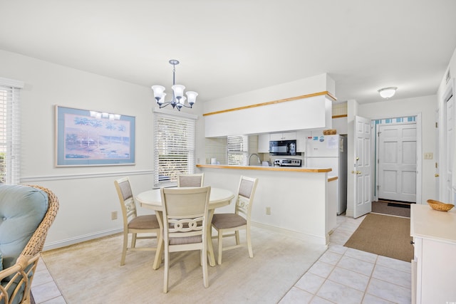 dining area with a chandelier, light tile patterned flooring, and baseboards