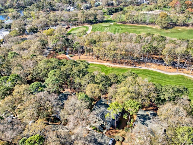 aerial view of property and surrounding area with a golf course and a tree filled landscape