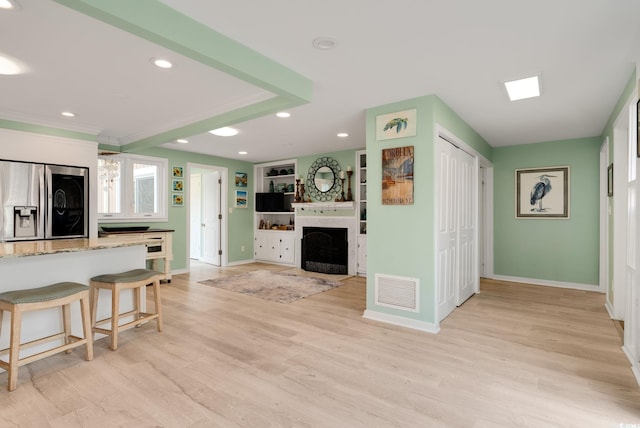 living area featuring light wood finished floors, a fireplace, baseboards, visible vents, and recessed lighting