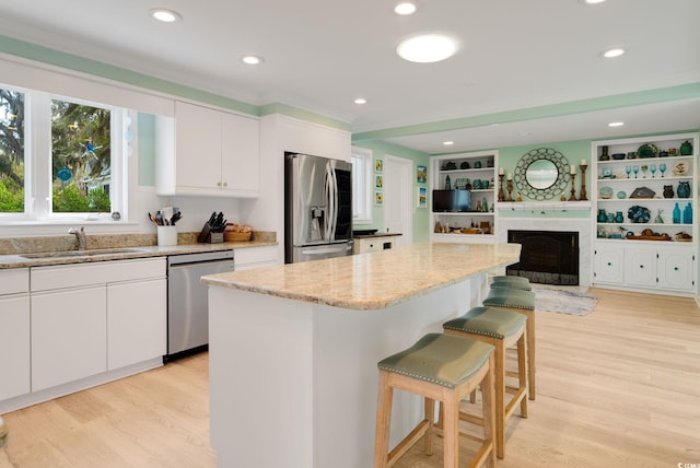 kitchen featuring a center island, a sink, a breakfast bar, light wood-type flooring, and appliances with stainless steel finishes