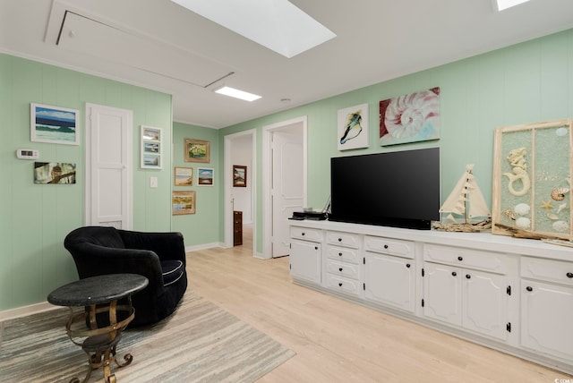 living area featuring light wood finished floors, attic access, and baseboards