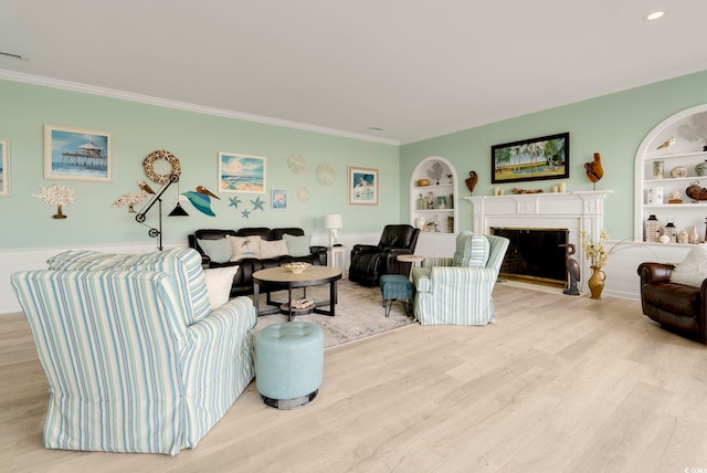 living room featuring built in shelves, a fireplace with flush hearth, crown molding, and light wood-style flooring