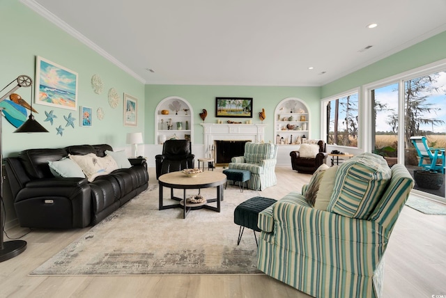 living area featuring crown molding, built in features, wood finished floors, and a fireplace