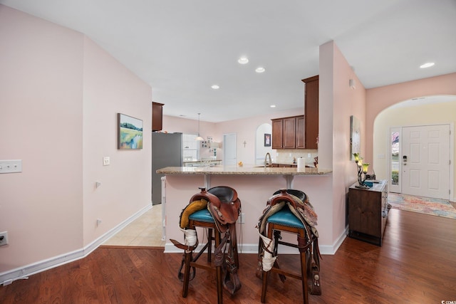 1112 Raven Cliff Ct, Conway, SC 29526 - kitchen featuring arched walkways, light stone countertops, a kitchen bar, a peninsula, and recessed lighting