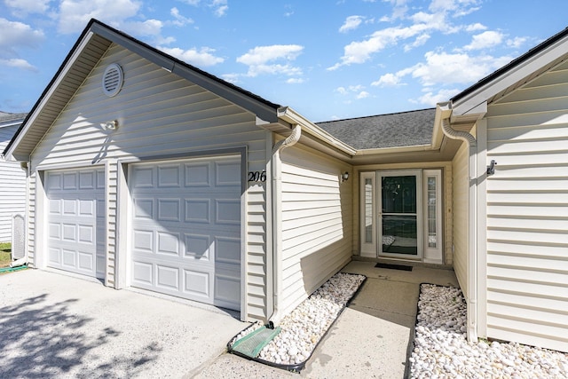 view of exterior entry featuring a shingled roof and a garage