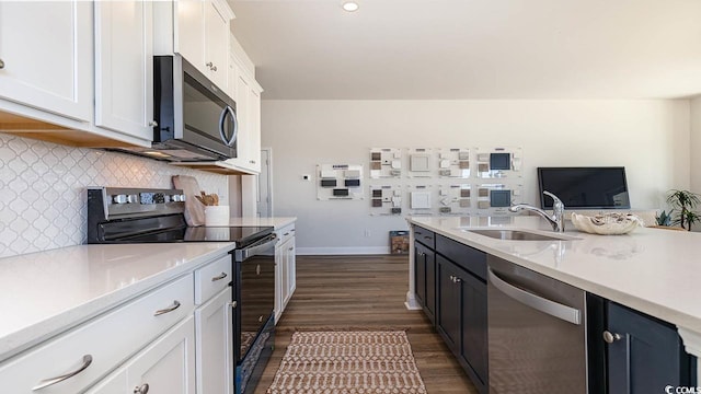kitchen featuring dark wood-style flooring, light countertops, white cabinets, stainless steel appliances, and a sink