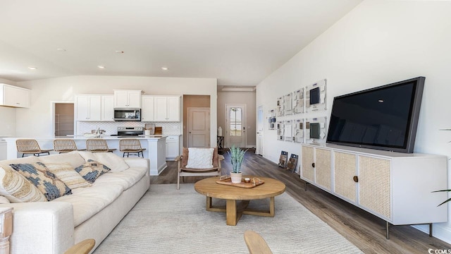 living area featuring recessed lighting, vaulted ceiling, and wood finished floors