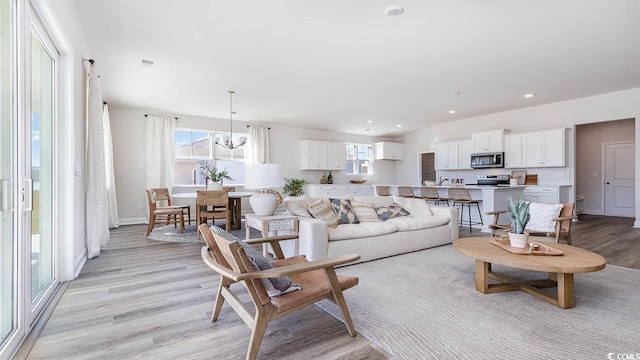living room with baseboards, a chandelier, recessed lighting, visible vents, and light wood finished floors