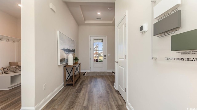 interior space featuring dark wood-style flooring, visible vents, baseboards, and a raised ceiling